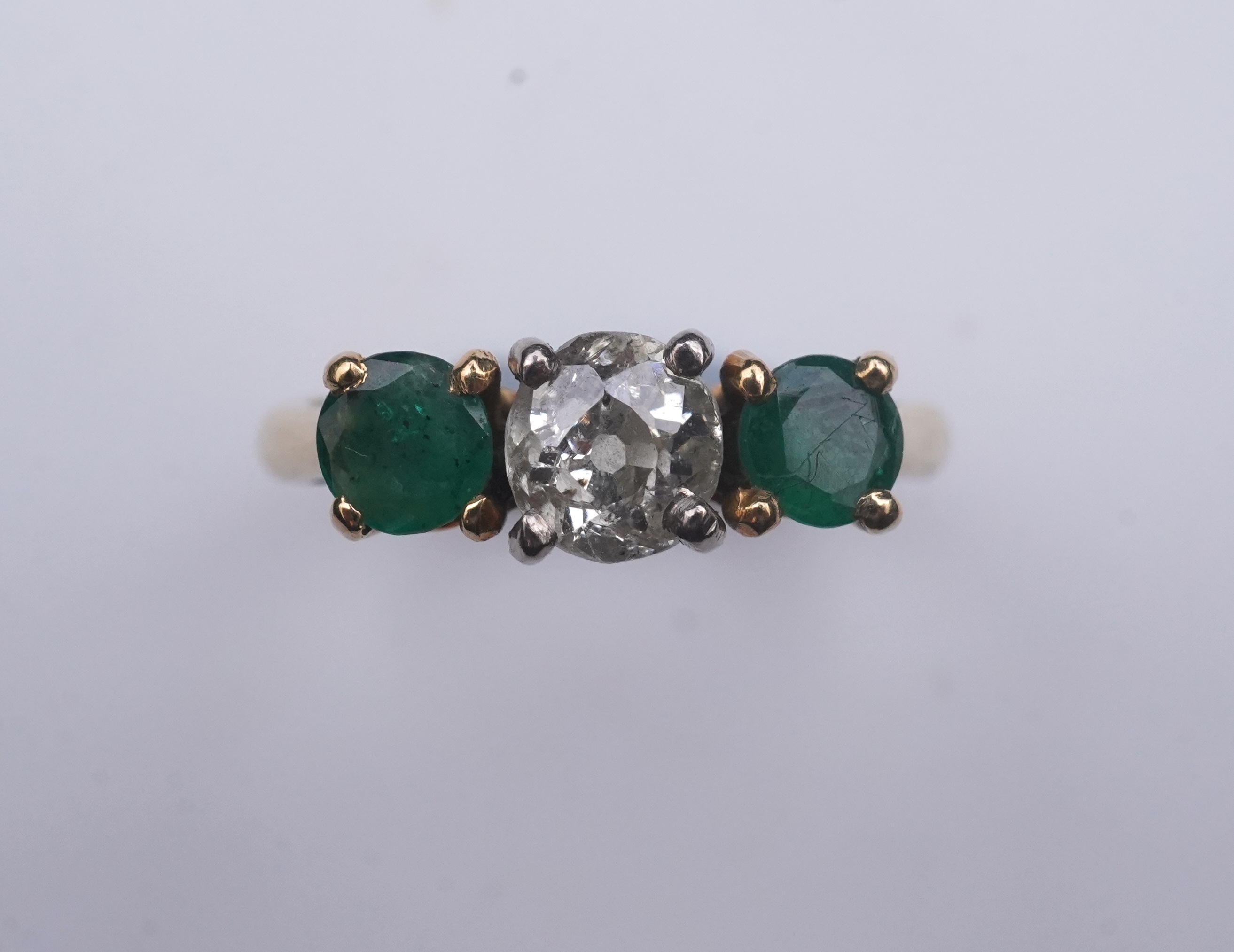 An emerald and diamond three-stone ring